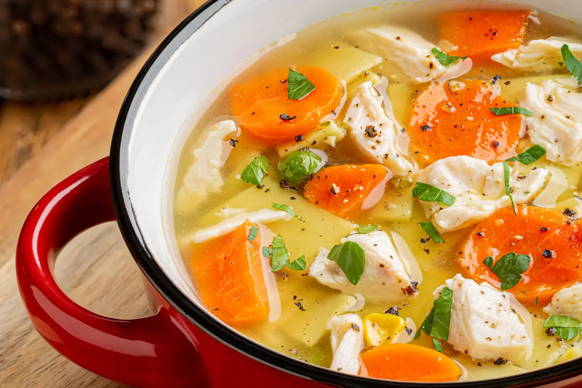 Warm and inviting bowl of gluten-free chicken noodle soup on a rustic wooden table.