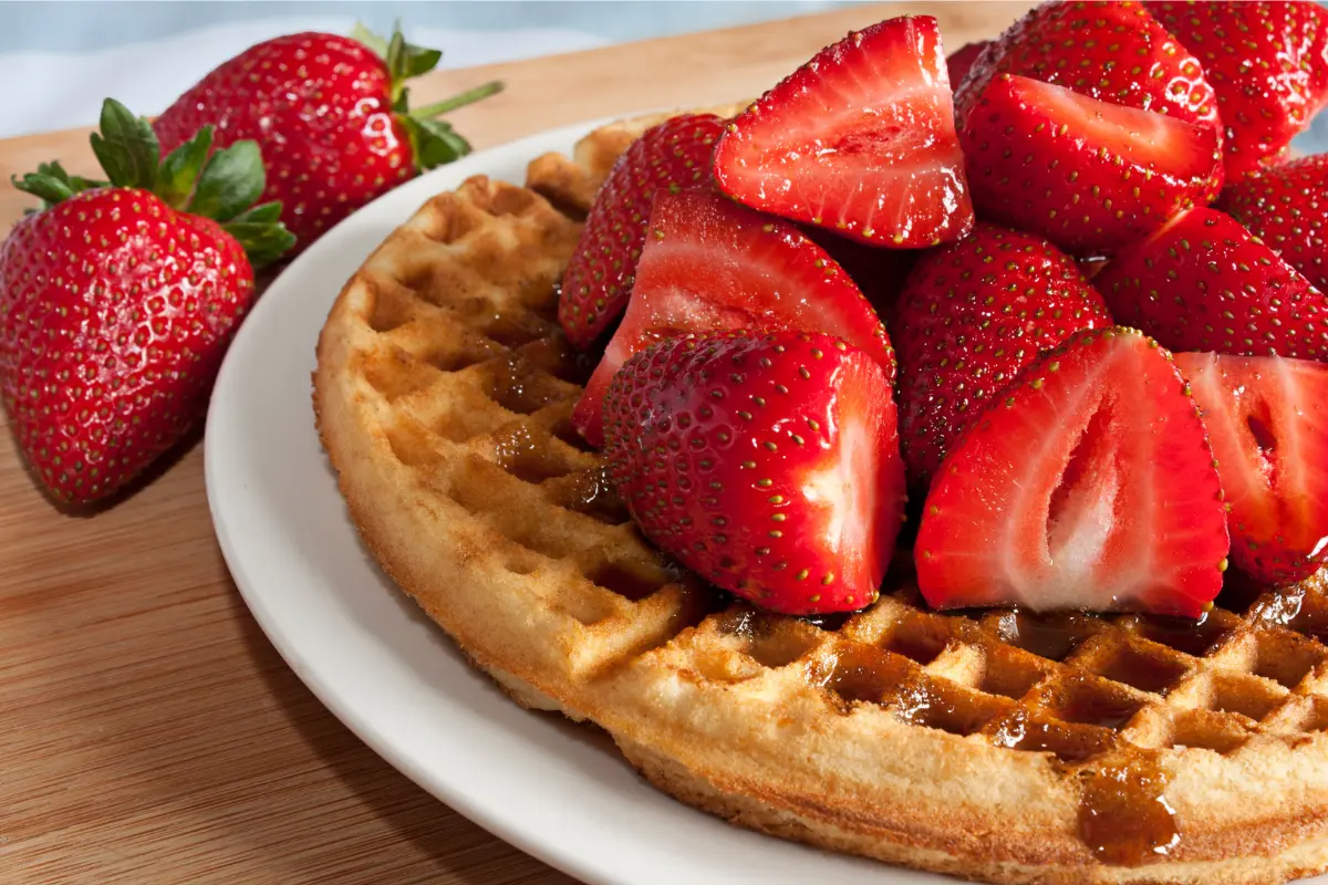 Stack of Kodiak protein waffles with fresh berries and honey on top.