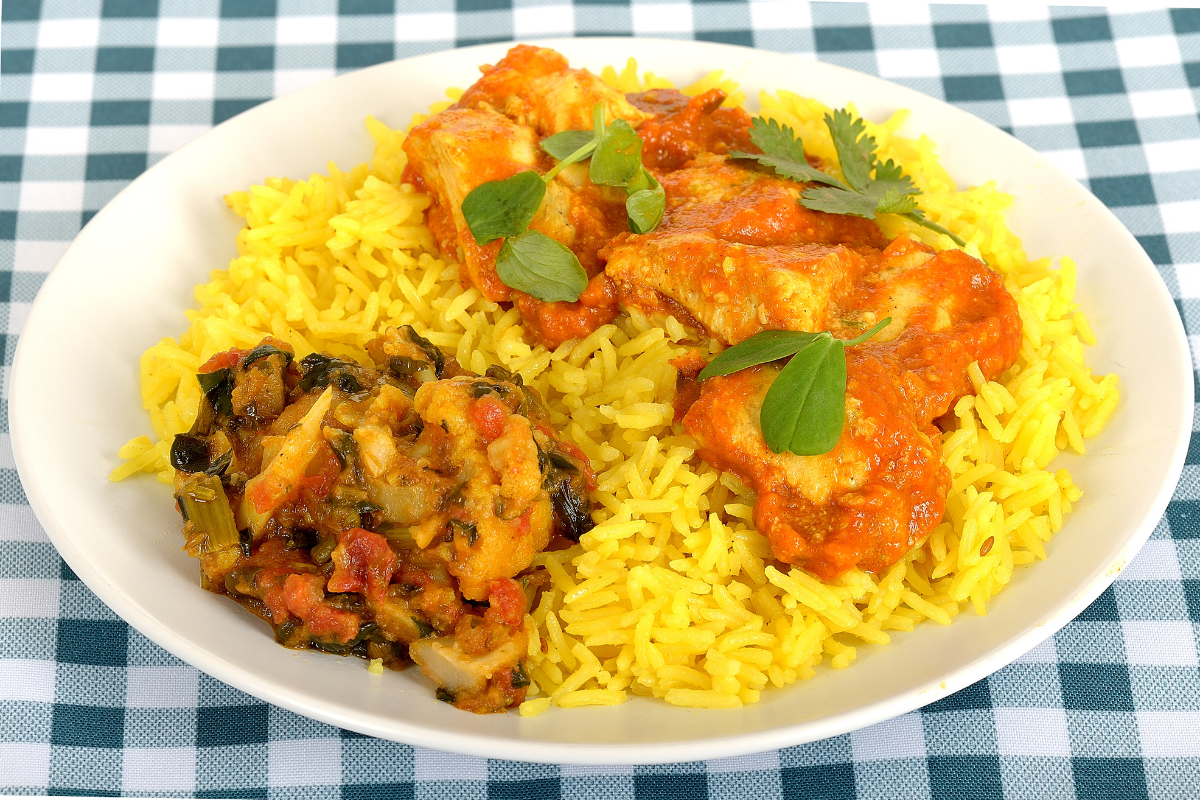 Yellow rice with cilantro garnish served with sautéed bell peppers, tomatoes, black beans, grilled chicken, and shrimp, seasoned with turmeric, cumin, and paprika.